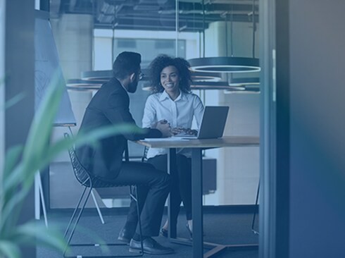 A man and a woman are having a discussion in front of a laptop